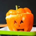 An orange stuffed pepper with a Halloween face with text overlay that says "Shepherd's Pie Jack O'Lantern Stuffed Peppers".