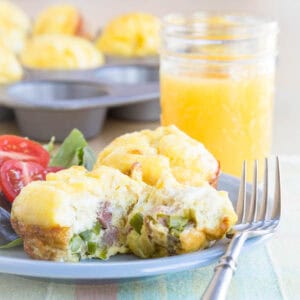 Cheesy Ham Asparagus Egg Bites on a plate with a piece cut off of one.