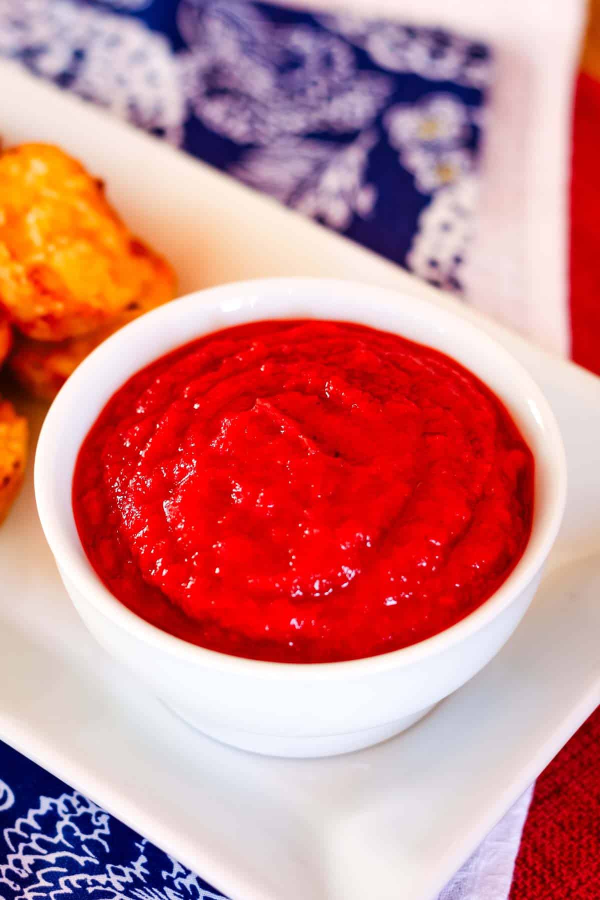 A white bowl filled with homemade catsup on top of a platter.