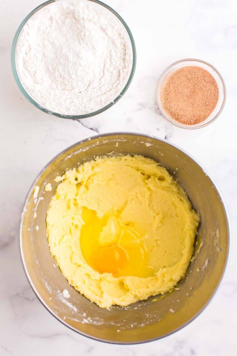 Creamed butter and sugar in a mixing bowl with one egg added to it.