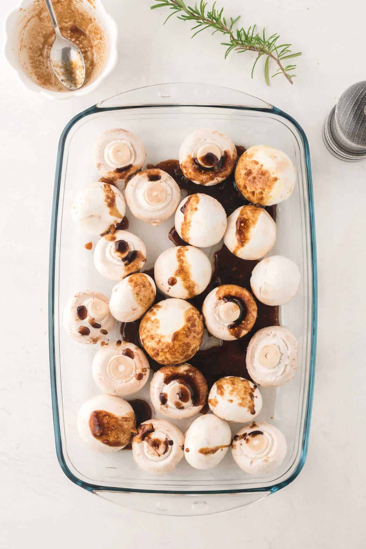 Mushrooms in a baking dish drizzled with balsamic marinade.