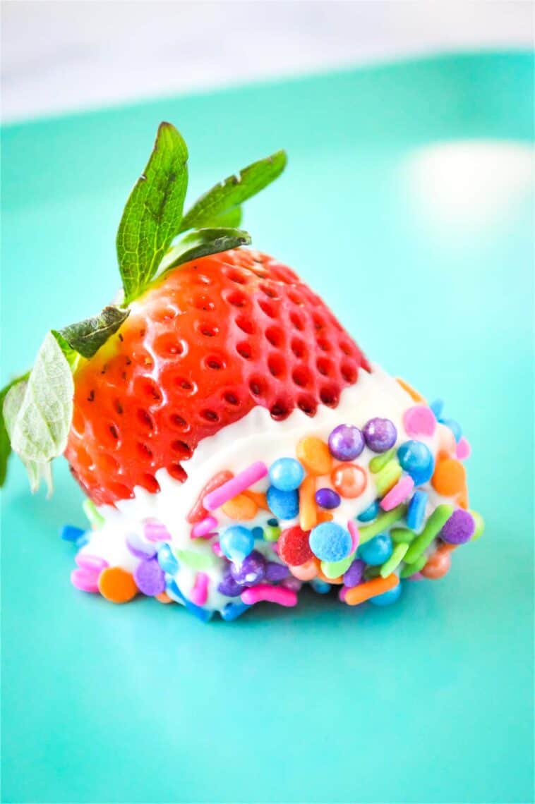 One white chocolate strawberry with sprinkles on a plate.