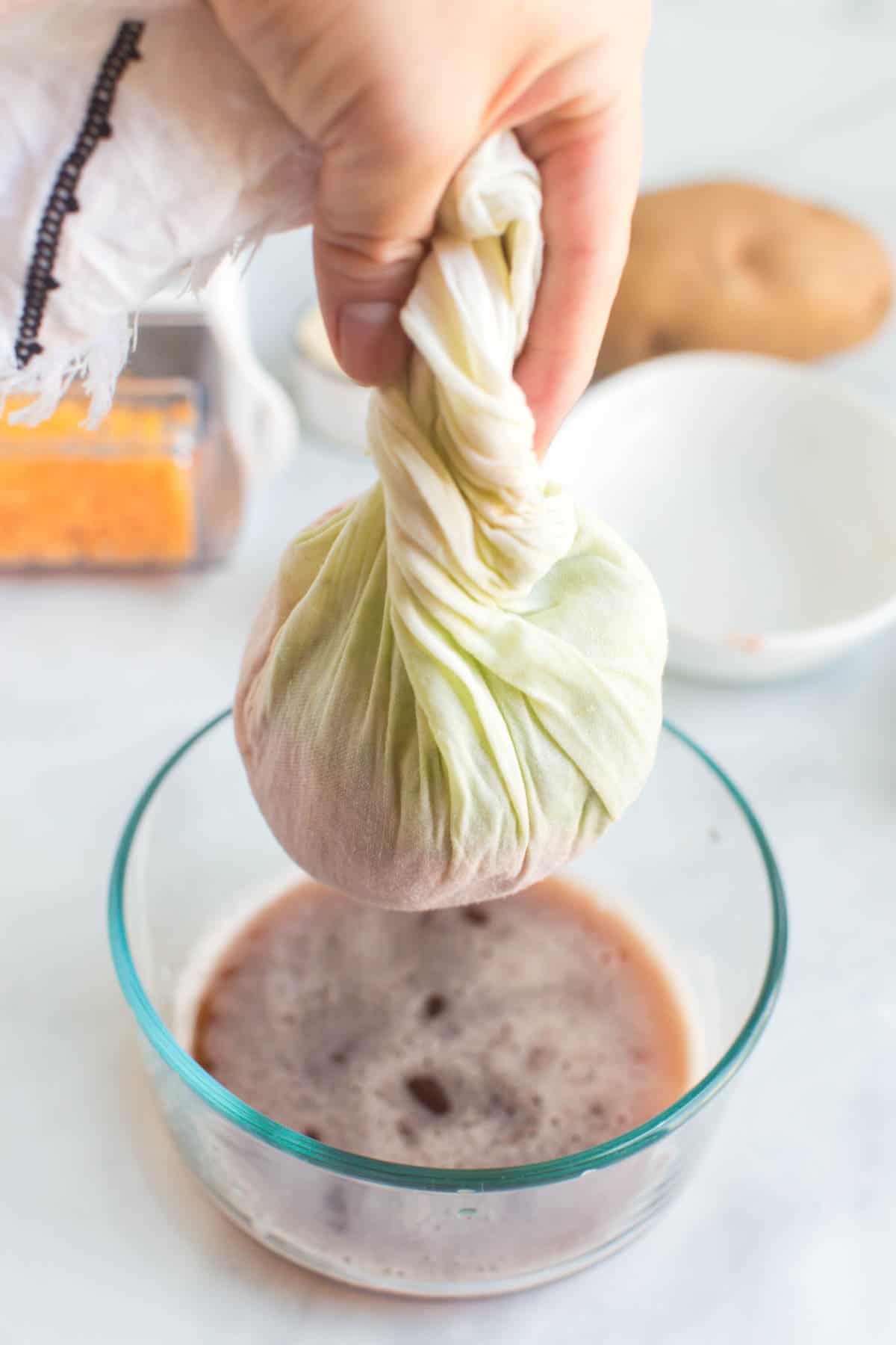 Shredded potatoes and zucchini wrapped in a towel and squeezing the liquid out.