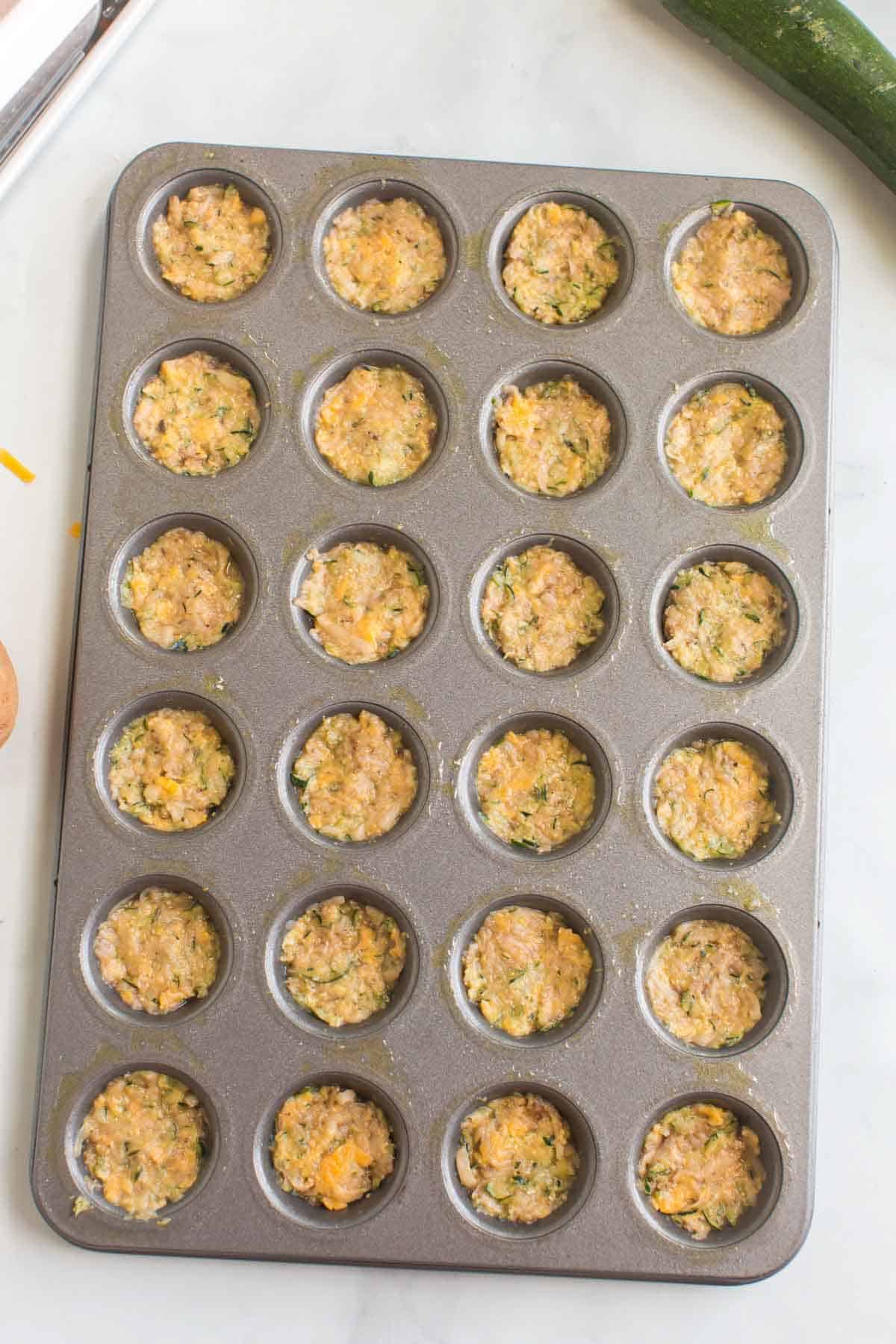 Packing Zucchini Tater Tot mixture in a muffin pan to bake.