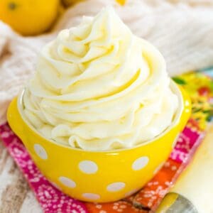Lemon buttercream piped into a swirl in a yellow bowl with white polka dots.