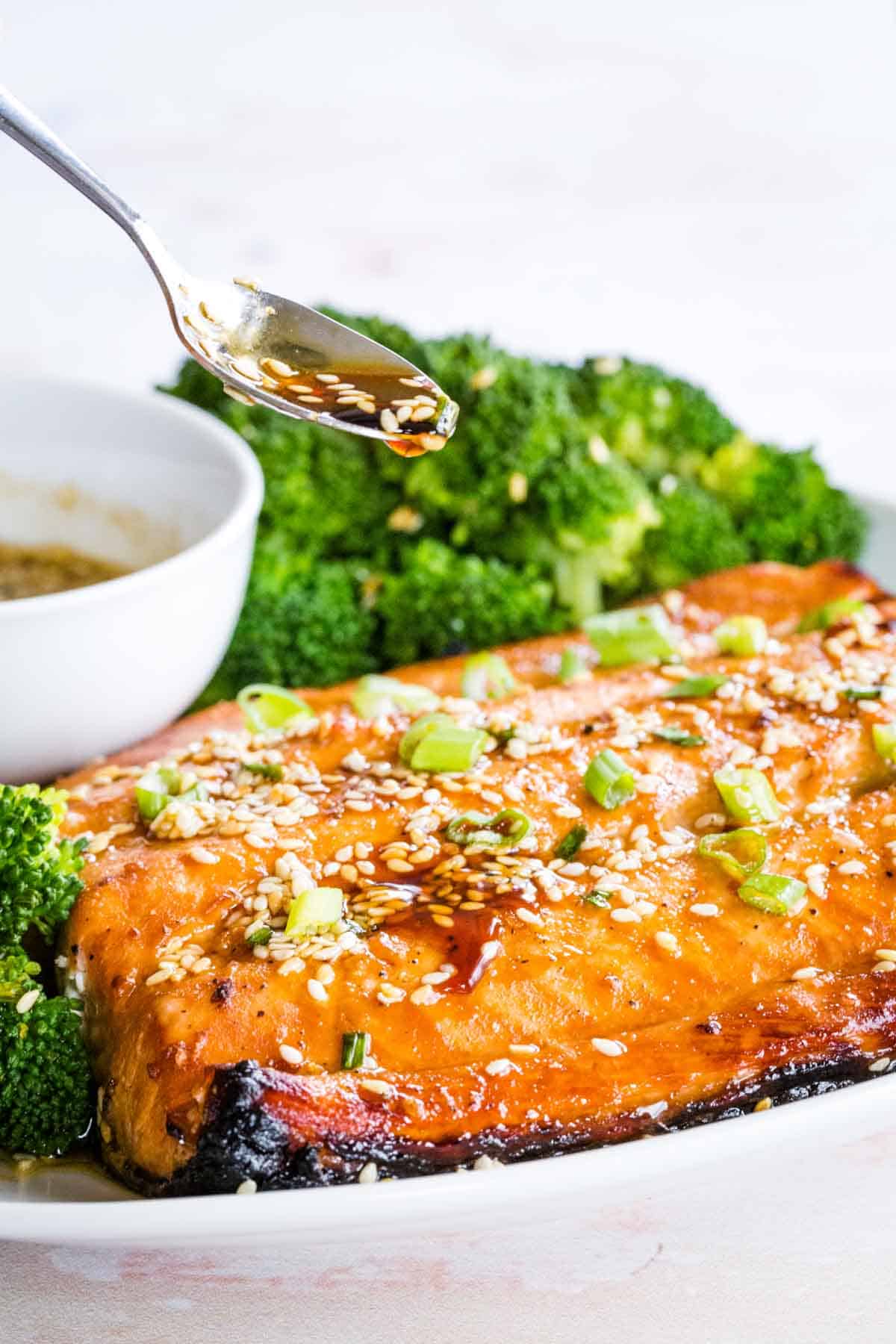 Sauce dripping off a spoon onto Sesame Maple Glazed Salmon.