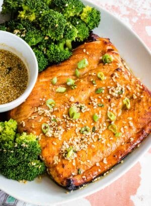 Broiled salmon on a plate with maple sesame glaze and broccoli.