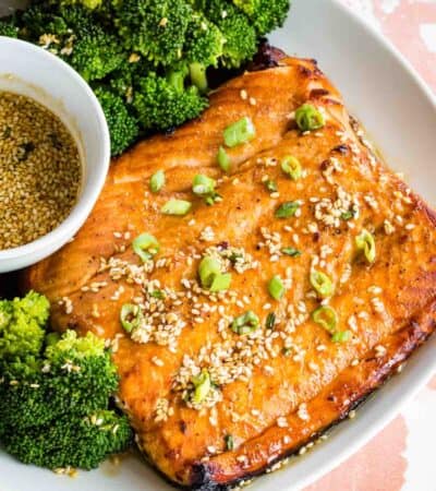 Broiled salmon on a plate with maple sesame glaze and broccoli.