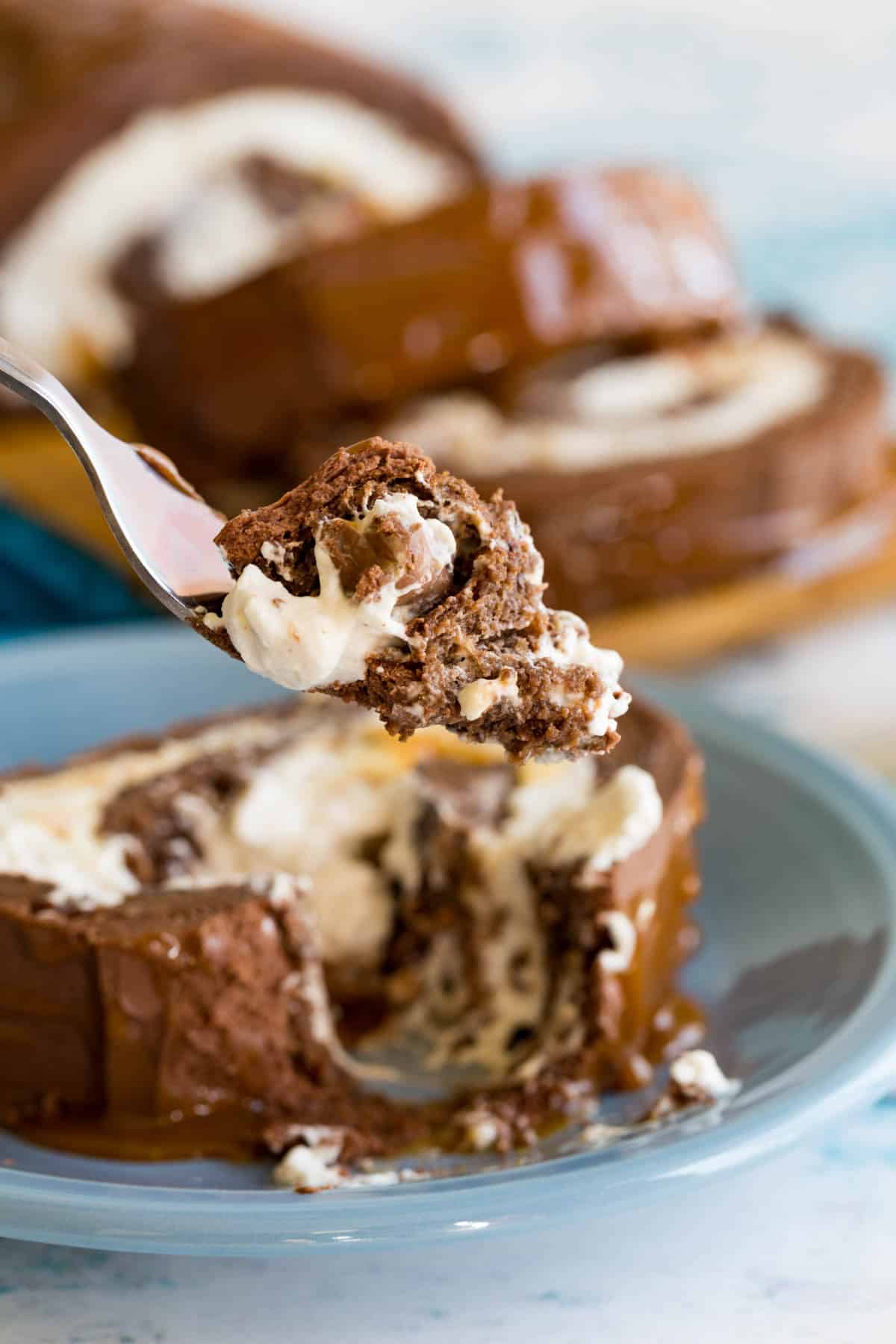 Fork holding a bite of Flourless Chocolate Cake Roll with caramel.