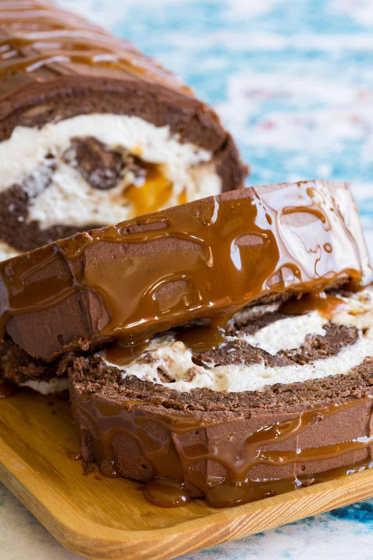 Slices of Milky Way Flourless Chocolate Cake Roll on a wooden serving platter.