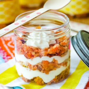 Layers of carrot cake and cream cheese frosting forming a trifle in a small jar.