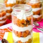 A jelly jar with layers of crumbled carrot cake and cream cheese filling with text overlay that says "Carrot Cake Trifles".