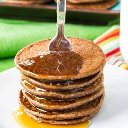 A stack of mini chocolate Banana Blender Pancakes with syrup dripping off of them.