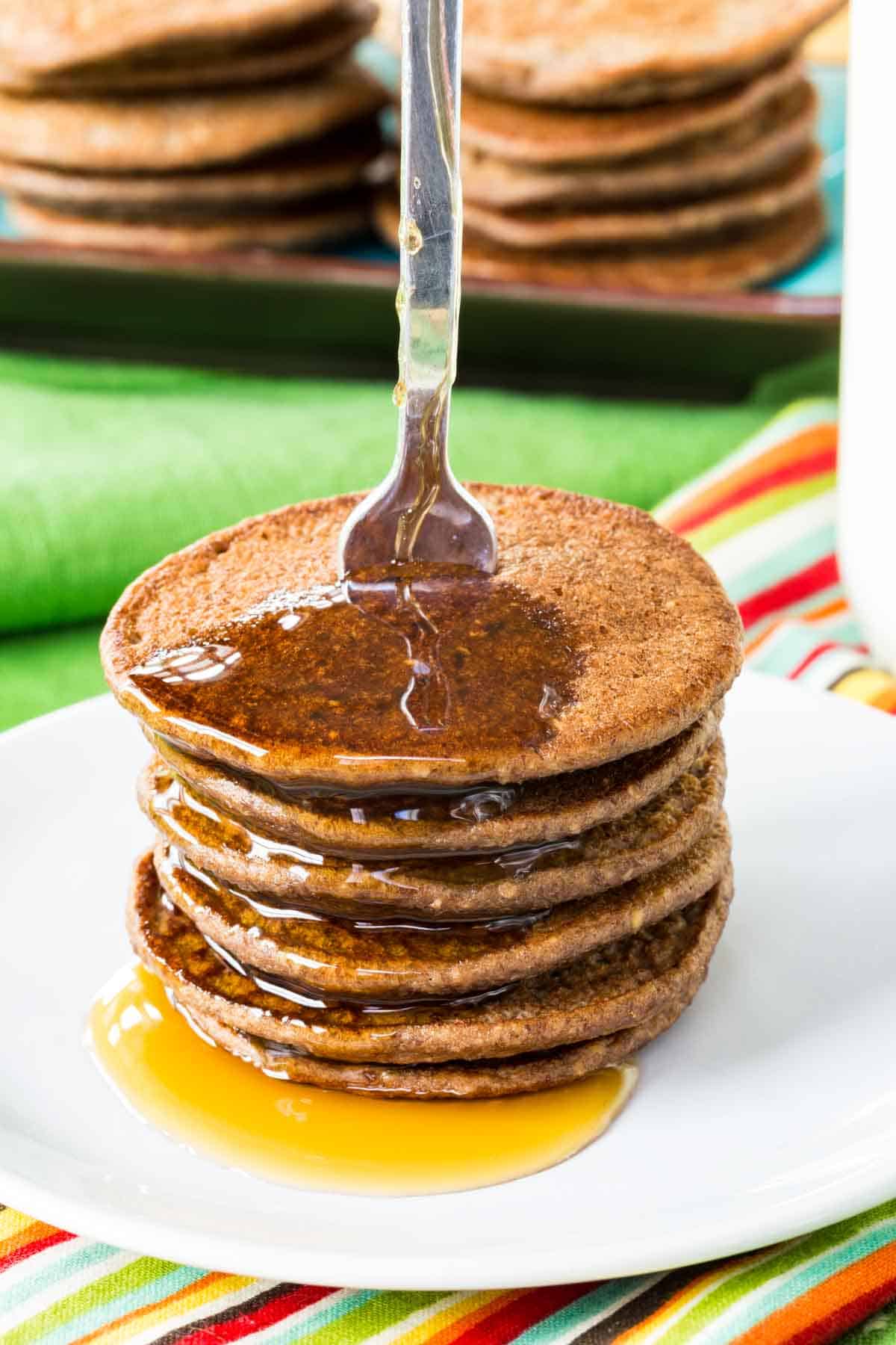A stack of mini chocolate Banana Blender Pancakes with syrup dripping off of them.