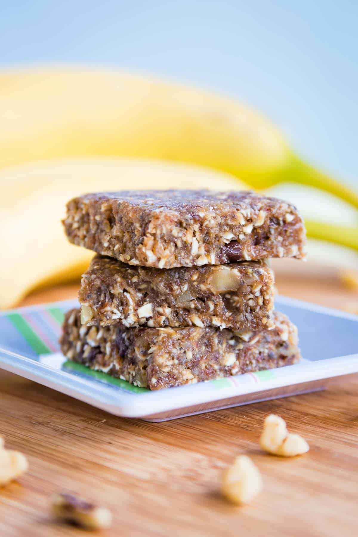 Three No-Bake Banana Bars in a stack on a small blue square plate on top of a wooden board.