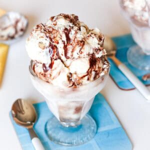Butter Pecan Fudge Ripple Ice Cream in a glass dish with a small spoon next to it.