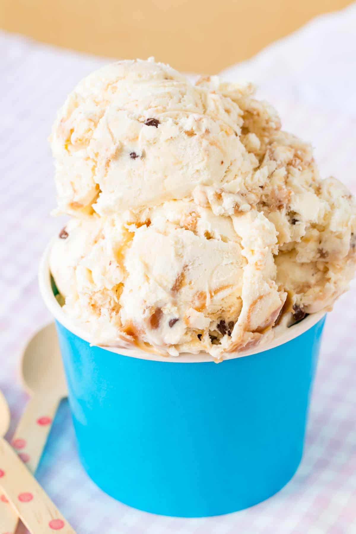 Ice cream with caramel, toffee, and chocolate chips in a blue cup.