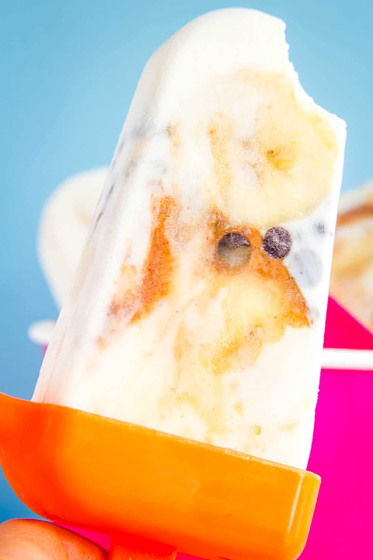 A banana yogurt popsicle with a bite taken out.