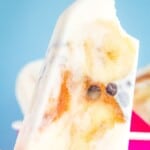 A frozen yogurt pop with a bite taken out with text overlay that says "Peanut Butter Banana Popsicles".