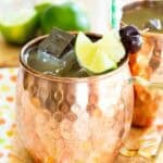 A pina colada moscow mule garnished with fruit on toothpick in a copper mug.