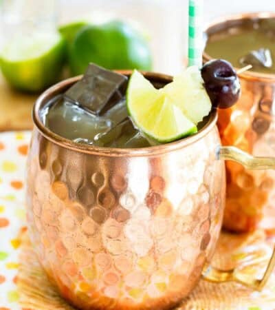 A pina colada moscow mule garnished with fruit on toothpick in a copper mug.