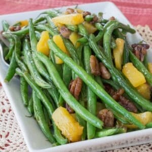 A serving dish of pineapple green beans with pecans.