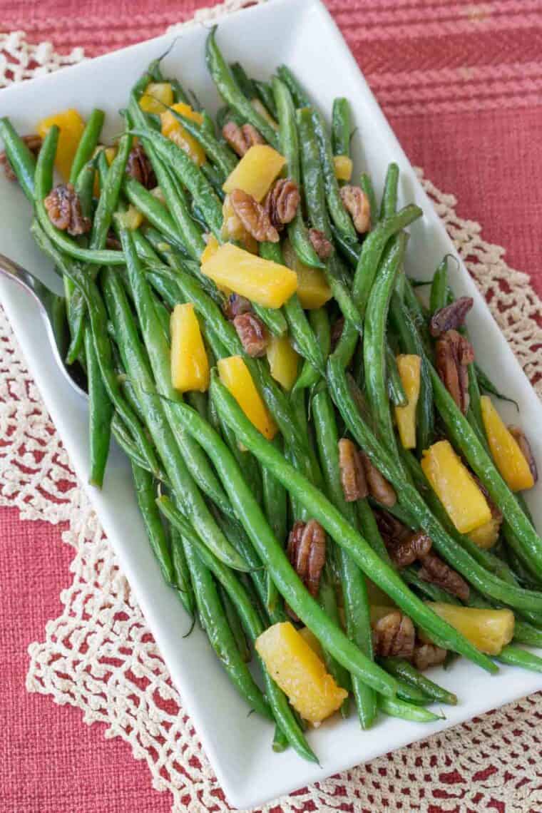 An overhead view of a plate of green beans on a placemat on a table.