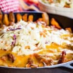 A closeup of a pan of pulled pork fries topped with melted cheese and coleslaw.