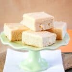 Pumpkin spice frosted sugar cookie bars stacked on a green cake stand.