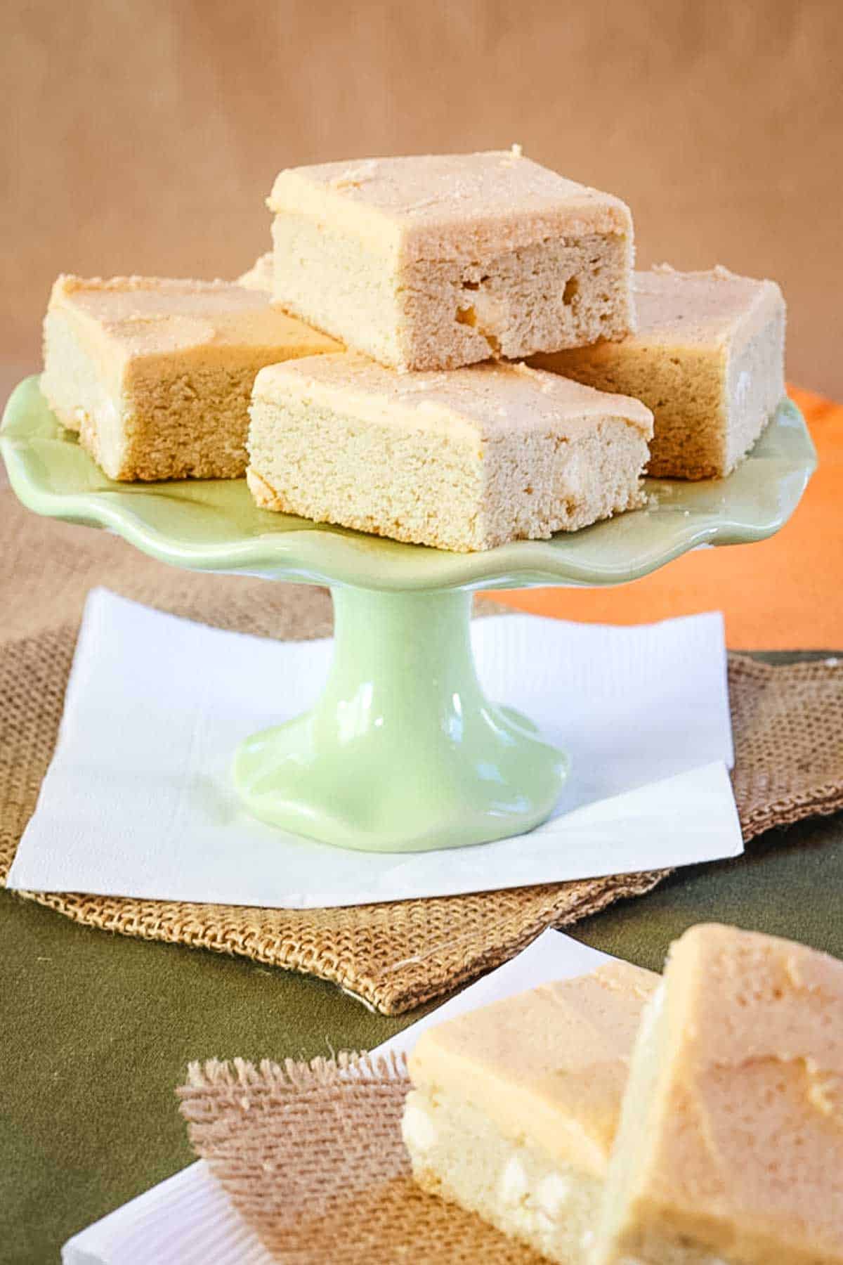 White Chocolate Chip Sugar Cookie Bars arranged on a cake stand with a couple in front.