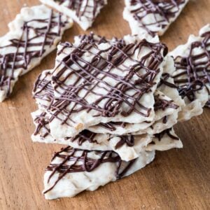 Pieces of Pumpkin Spice White Chocolate Bark stacked on a cutting board.