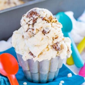 No churn puppy chow ice cream in a small metal cup dripping onto a blue napkin.