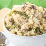 Quinoa Pilaf with roasted asparagus and mushrroms plus sliced almonds in a white serving bowl.