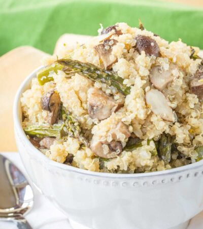 Quinoa Pilaf with roasted asparagus and mushrroms plus sliced almonds in a white serving bowl.