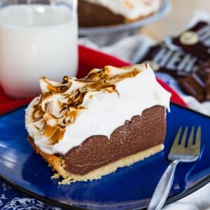 A slice of s'mores pie on a blue plate with a fork in it.