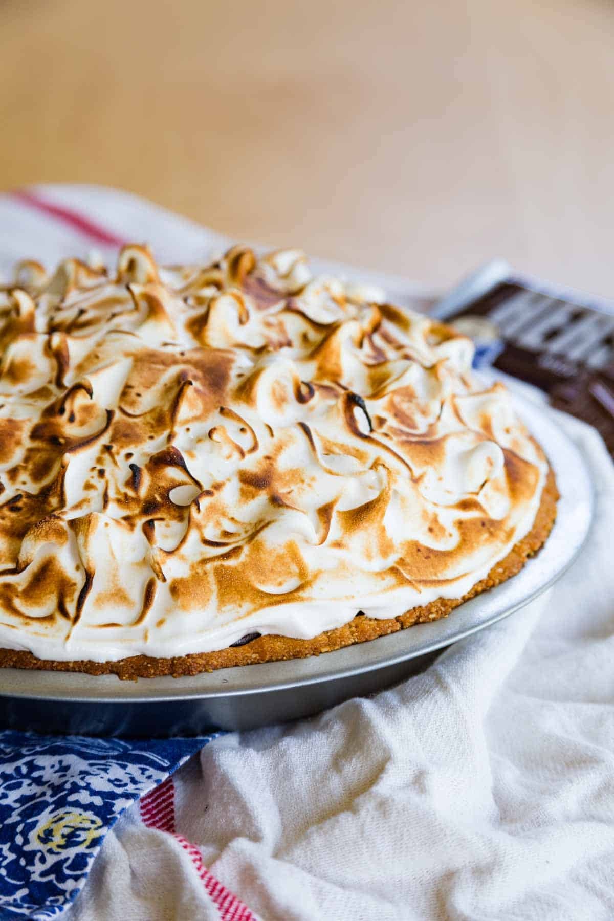 A whole s'mores pudding pie in a pie plate, topped with toasted marshmallow meringue.