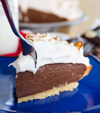 A fork digging into the corner of a slice of gluten-free s'mores pie on a blue plate.