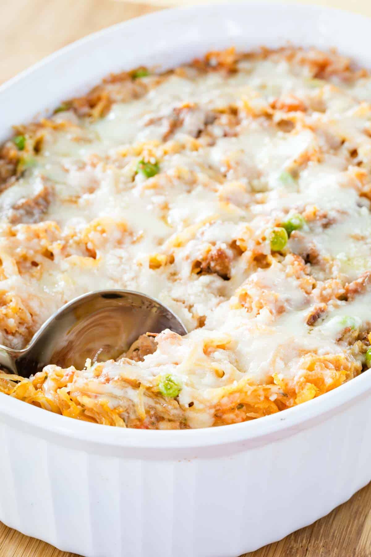 Spaghetti squash casserole in a baking dish with a serving spoon tucked into the corner.