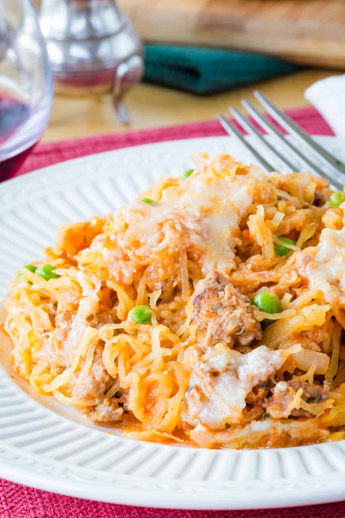 Close up of a serving of spaghetti squash casserole on a plate with a fork.