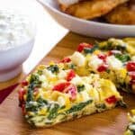 Spinach Frittata being cut into pieces on a cutting board.