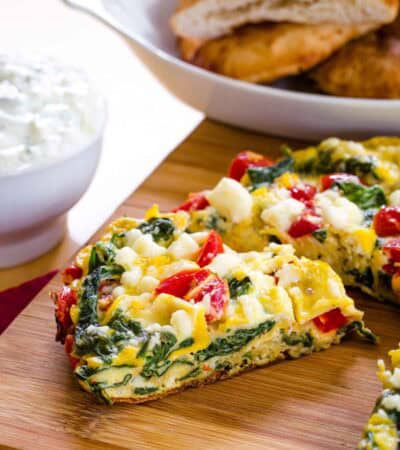 Spinach Frittata being cut into pieces on a cutting board.