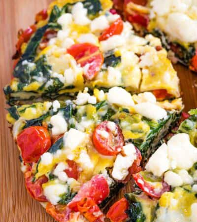 Pieces of Spinach Frittata with feta and tomatoes from above on a cutting board.
