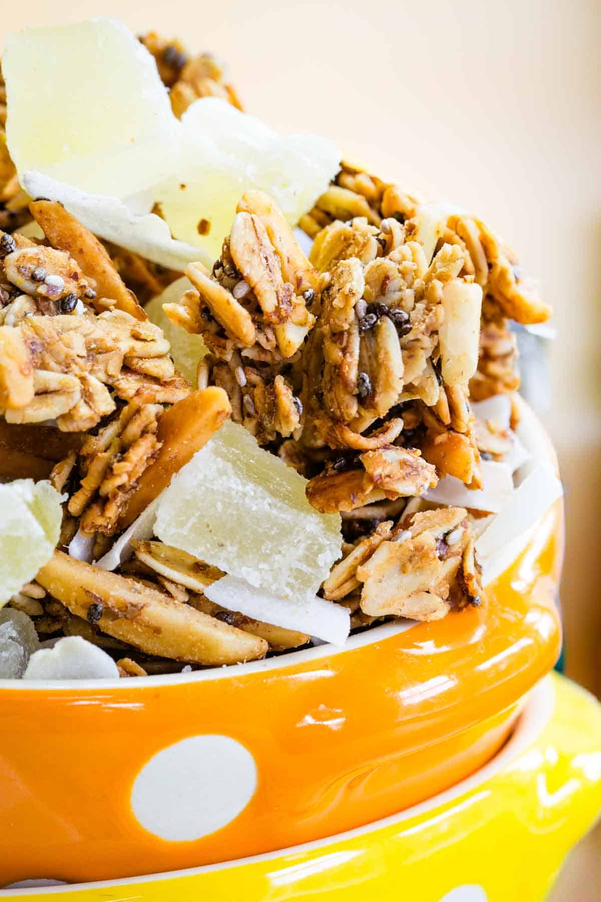 A closeup of granola with coconut flakes and pieces of dried pineapple.