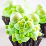 A chocolate cupcake in a black wrapper with green frosting and decorations with text overlay that says "Witch's Brew Halloween Cupcakes".