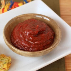 Homemade Worcestershire ketchup in a small green bowl on a white plate.