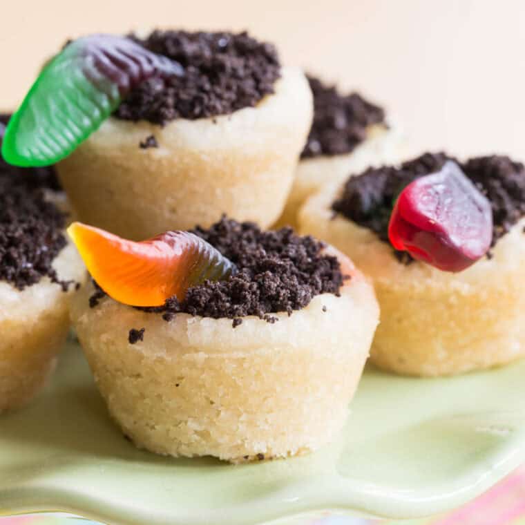 Dirt Cookies with sugar cookie cups filled with crushed Oreos and gummy worms on a green platter.