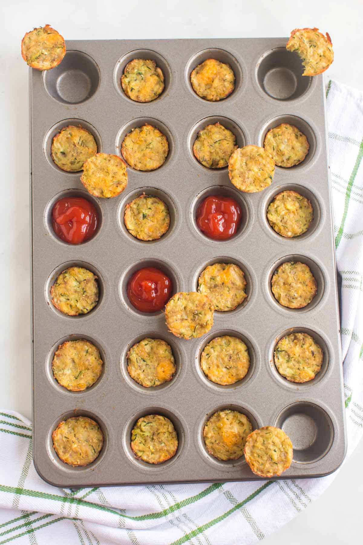Zucchini. Tots in a mini muffin pan with some removed to make spots for ketchup