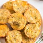 A plate of tater tots with flecks of zucchini with text overlay that says "Cheesy Zucchini Tots".