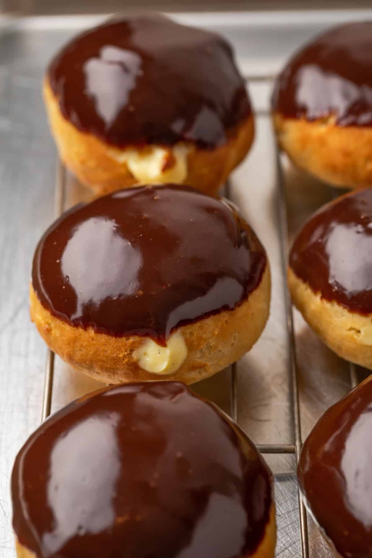 A tray of chocolate-glazed cream-filled gluten-free Boston Cream Pie donuts.