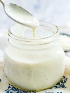 A jar of homemade alfredo sauce with a spoon.